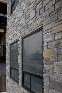 a brick building with two windows on the side and one window in the middle that is partially closed