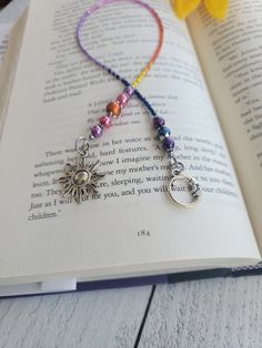 an open book with some beads on it and a sun charm hanging from the pages