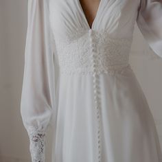 a woman wearing a white wedding dress with long sleeves