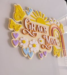 a sign that says grace and may with flowers, hearts, butterflies, and a rainbow