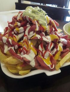 a plate filled with french fries covered in ketchup and mayonnaise sauce