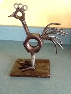 a metal bird sculpture sitting on top of a wooden table next to a blue wall