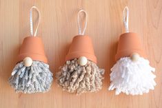 three different colored pom poms hanging from hooks on a wooden surface with string