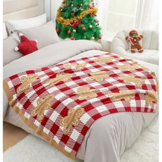 a christmas tree in the corner of a bedroom with a red and white checkered bedspread