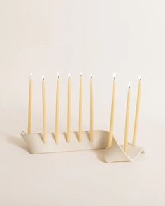 five candles are lined up in a row on a white stand with one candle sticking out of it