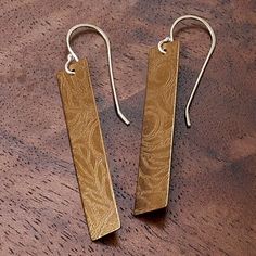 pair of gold earrings on wooden table with metal hooks