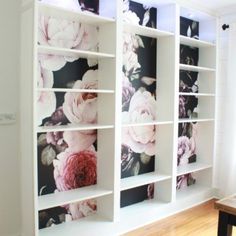 a white bookcase with flowers painted on the front and back sides, along with a wooden table