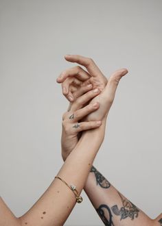 two hands reaching up to each other with tattoos on their arms and wristbands