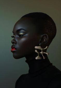 a woman with black hair and large earrings on her face, looking off to the side