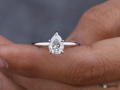 a woman's hand holding a diamond ring with the center stone in white gold