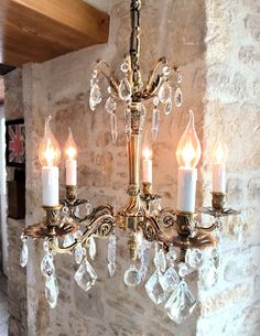 a chandelier hanging from a stone wall with crystal drops on the bottom and sides