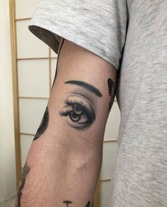 a man with a cross tattoo on his arm and eye looking up at the sky