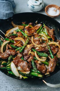 beef and asparagus stir fry in a wok with chopsticks on the side