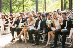 a group of people sitting next to each other in front of a forest filled with trees