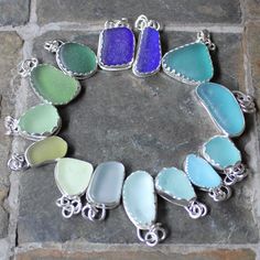 a bracelet made out of sea glass sitting on top of a stone floor