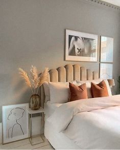 a bed with white sheets and pillows in a bedroom next to pictures on the wall