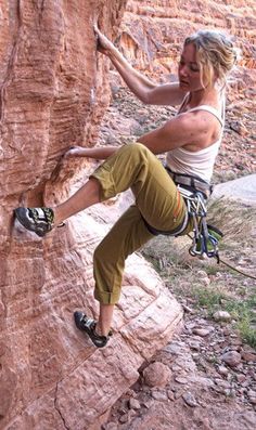 a woman climbing up the side of a cliff