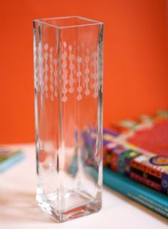 a clear vase sitting on top of a table next to a stack of colored books