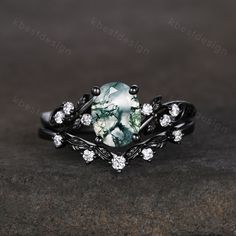 a ring with a green stone surrounded by white diamonds on a dark surface, in the middle