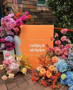 a bunch of flowers that are sitting on the ground next to a sign with words