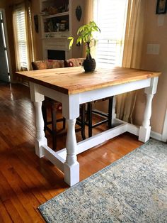 a wooden table sitting on top of a hard wood floor next to a rug and window