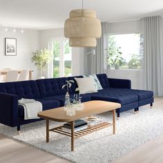 a modern living room with blue couches and white rugs on the hardwood floor