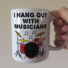 a hand holding a coffee mug that says, i hang out with musicians on it