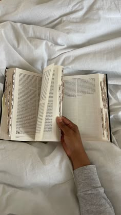 a person laying in bed with an open book on top of their head and hands