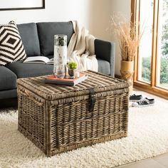 a living room with a gray couch and wicker coffee table