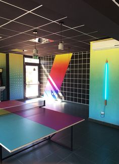 a ping pong table in an empty room with neon lights on the walls and floor