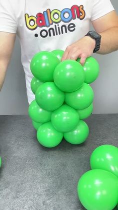 a man is placing green balloons on top of each other