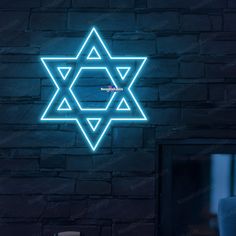 the star of david neon sign is lit up against a brick wall