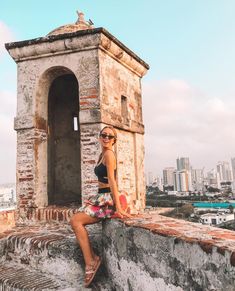 a woman sitting on top of a stone wall