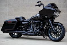 a black motorcycle parked in front of a brick wall