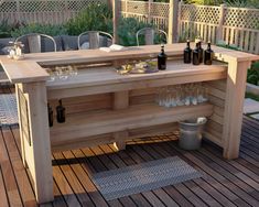 a wooden table with bottles and glasses on it in the middle of a deck area