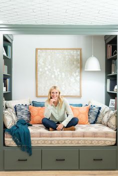 a woman sitting on top of a couch next to a book shelf filled with books