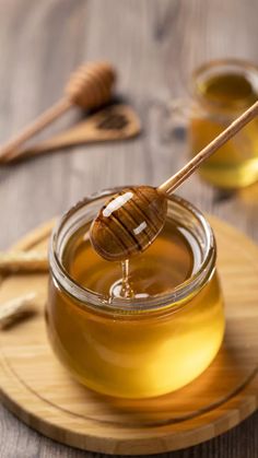 a jar of honey and a wooden spoon on a plate with some honey in it