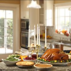 a turkey sitting on top of a table next to other foods and candles in a kitchen