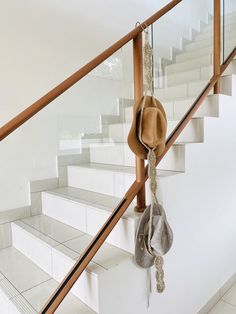 two hats hanging on the handrail next to some white stairs with metal railings