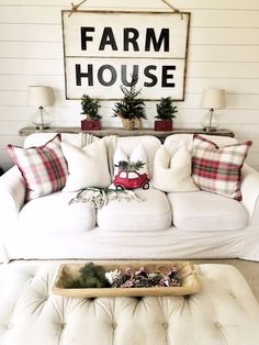 a living room with white couches and christmas decorations on the coffee table in front of a farm house sign