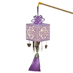 a purple wind chime hanging from a wooden pole on top of a white wall