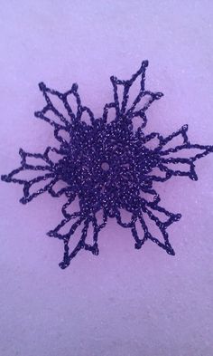 a close up of a purple object on a white surface with snow flakes in the background