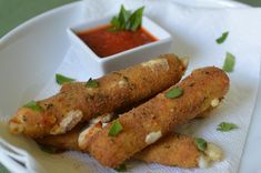 some food is on a white plate with a small bowl of sauce and tomatoes in the background