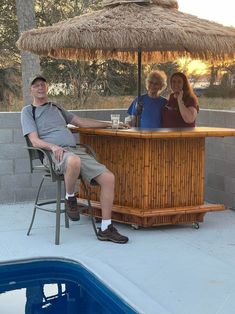 two people sitting at an outdoor bar next to a pool