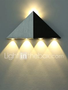 three lights are on the wall in front of a white wall with a triangular shaped light