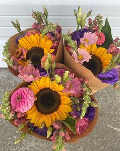 three brown paper bags filled with flowers on top of a cement floor next to a white door