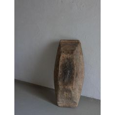 a wooden vase sitting on top of a cement floor next to a white wall,