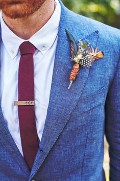 a man wearing a blue suit with a red tie and flower boutonniere