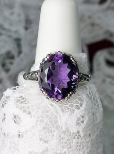 "Natural Purple Amethyst Ring Description Edward Design#70 (smaller version) MADE TO ORDER Inspired by Edwardian jewelry of the early 1900s, I now offer this lovely Antique reproduction ring in sterling silver. This gorgeous ring is set with a stunning 3.32ct Natural purple amethyst gemstone. This genuine amethyst has excellent color and clarity. The oval cut amethyst is 12mm (1/2th of an inch) Long by 10mm Wide (3/8th\"). The ring sits 6mm off the finger. The inside of the band s marked 925 for Oval Purple Filigree Amethyst Ring, Oval Purple Amethyst Ring With Filigree, Purple Oval Amethyst Ring With Filigree, Oval Amethyst Ring With Accent Stones For Anniversary, Purple Oval Filigree Rings, Purple Anniversary Rings With Intricate Design, Classic Oval Amethyst Ring With Accent Stones, Classic Oval Purple Gemstones, Fine Jewelry Amethyst Ring With Intricate Design For Wedding