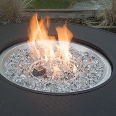 a fire pit with ice and rocks on it's sides, surrounded by grass